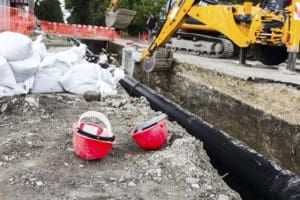 plumbing for septic system being installed with workers in the excavated ditch