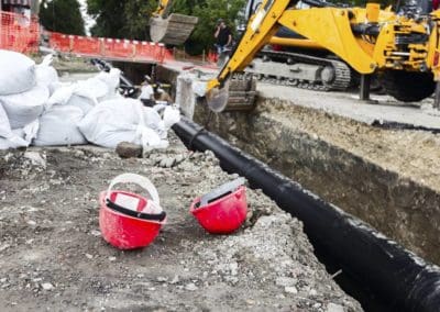 plumbing for septic system being installed with workers in the excavated ditch