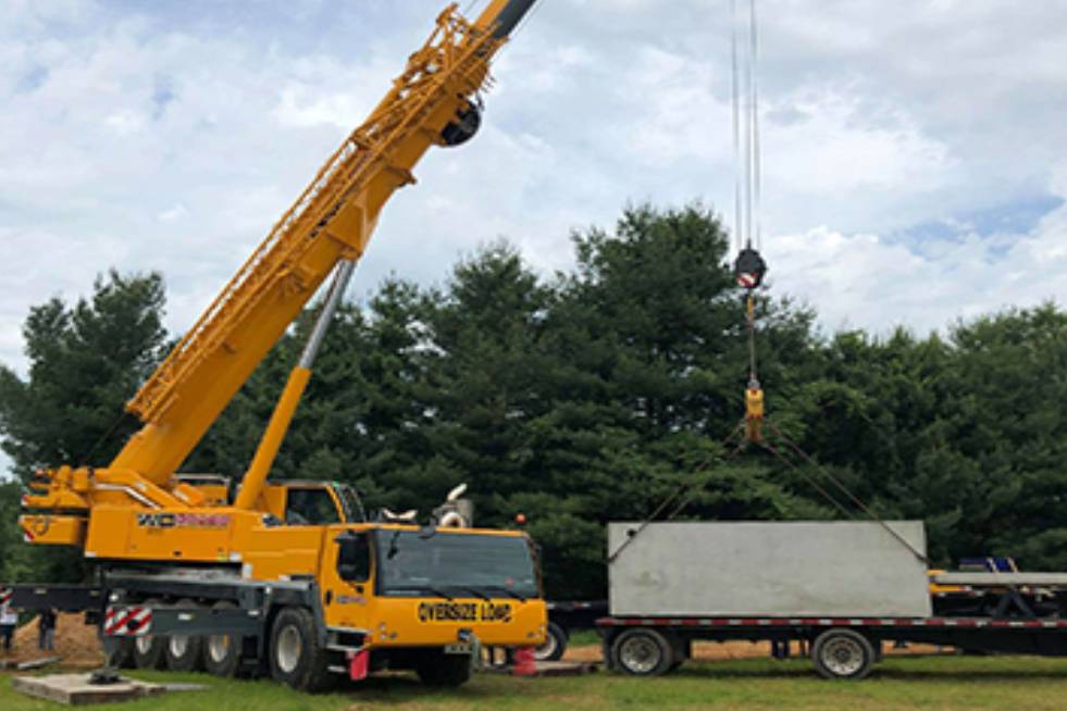 crane a crane is holding the concrete structure of the septic system