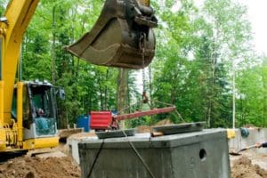 an excavator is holding the concrete structure of septic system