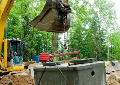 an excavator is holding the concrete structure of septic system
