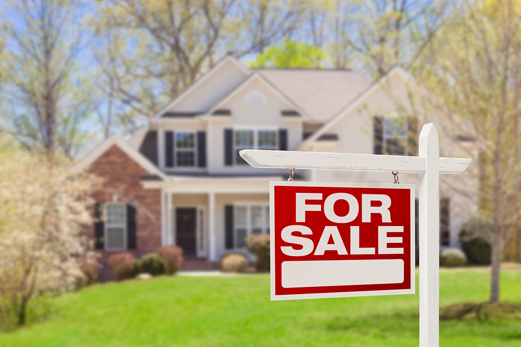 For sale sign in from of two story traditional home in rural area